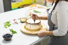 Cukierniczka gniesie ciek?? czekolad? od ciasto torby na bia?ym kremowym ciastko torcie na drewnianym stojaku _ zdjęcia stock Cukierniczka gniesie ciek?? czekolad? od ciasto torby na bia?ym kremowym ciastko torcie na drewnianym stojaku _ zdjęcia stock