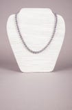 Cultured Black Pearls Necklace on a Display Stand. On gray background Stock Photos Cultured Black Pearls Necklace on a Display Stand. On gray background Stock Photos