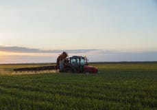 Cultures de pulvérisation de tracteur au coucher du soleil photos stock Cultures de pulvérisation de tracteur au coucher du soleil photos stock