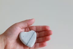 Cuore della tenuta del bambino piccolo della pietra a disposizione fotografie stock libere da diritti Cuore della tenuta del bambino piccolo della pietra a disposizione fotografie stock libere da diritti