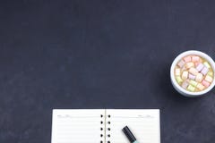 Cup with coffee and marshmallows, blank open notebook with pen on abstract black background. View from above. Flat layout. space royalty free stock photos Cup with coffee and marshmallows, blank open notebook with pen on abstract black background. View from above. Flat layout. space royalty free stock photos