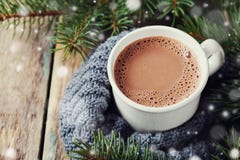 Cup of hot cocoa or hot chocolate on knitted background with fir tree and snow effect