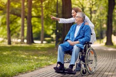 Curi la mostra del qualcosa l'uomo anziano sulla sedia a rotelle Immagini Stock Curi la mostra del qualcosa l'uomo anziano sulla sedia a rotelle Immagini Stock