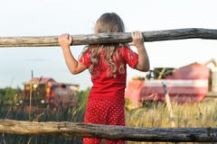 Curious farm girl wearing polka dot kids pans looking at field with working red combine harvesters royalty free stock photo Curious farm girl wearing polka dot kids pans looking at field with working red combine harvesters royalty free stock photo