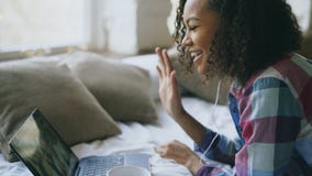 Curly african american young woman having video chat with friends using laptop camera while lying on bed royalty free stock photo Curly african american young woman having video chat with friends using laptop camera while lying on bed royalty free stock photo
