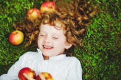 Curly Girl Lies On The Grass With Apple And Smiling. Stock Photos