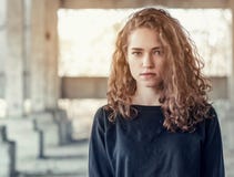 Curly hair. Beautiful girl on background of an abandoned concrete building. Light from behind at the industrial area