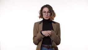 Curly haired european woman in stylish eyeglasses looking to the camera and showing silence gesture, keeping secrets