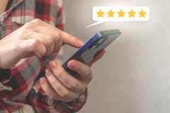 Customer pressing on smartphone screen with gold five star rating or feedback icon, excellent rank or best score point