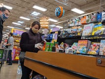 Customers with face masks and protective gloves loading groceries onto the checkout conveyor belt at a Fred Meyer grocery during