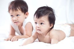Cute asian baby girl and her brother lying on stomach on the bed stock photo Cute asian baby girl and her brother lying on stomach on the bed stock photo