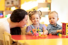 Cute babies play with carer or babysitter in nursery or kindergarten stock photo Cute babies play with carer or babysitter in nursery or kindergarten stock photo