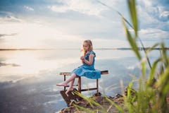 Cute child girl sitting on a wooden platform by the lake. Stock Photography Cute child girl sitting on a wooden platform by the lake. Stock Photography