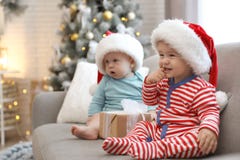 Cute Children In Santa Hats Sitting On Sofa At Home. Christmas Celebration Royalty Free Stock Photos
