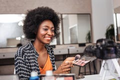 Cute dark-skinned woman with coral lipstick conducting online tutorial royalty free stock image Cute dark-skinned woman with coral lipstick conducting online tutorial royalty free stock image