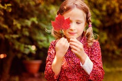 Cute dreamy child girl hiding behind red autumn leaf in the garden stock image Cute dreamy child girl hiding behind red autumn leaf in the garden stock image