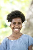 Sparkling eyes, beaming smile, cute girl with tropical blooms in hair. Fijian teen with huge fragipani blooms
