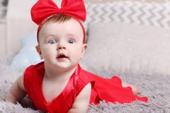 Cute funny baby in red dress and bow is on bed stock photography Cute funny baby in red dress and bow is on bed stock photography