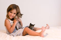 Cute Girl Holding Tabby Kitten On Soft Off-white Comforter Royalty Free Stock Image