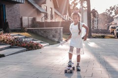 Cute girl wearing white dress and little crown standing on her skateboard stock photography Cute girl wearing white dress and little crown standing on her skateboard stock photography