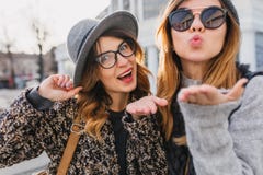 Cute girls wearing elegant glasses sending air kiss while spending time in weekend together. Charming friends having fun royalty free stock photos Cute girls wearing elegant glasses sending air kiss while spending time in weekend together. Charming friends having fun royalty free stock photos
