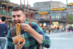 Cute guy eating Asian noodles outdoors royalty free stock photo Cute guy eating Asian noodles outdoors royalty free stock photo