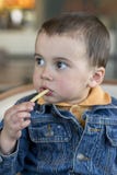 Cute little baby boy sitting at cafe eating tasty french fries. European royalty free stock photography Cute little baby boy sitting at cafe eating tasty french fries. European royalty free stock photography
