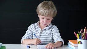 Cute little boy drawing at the table. Child from elementary school. Education concept. Back to school. stock footage Cute little boy drawing at the table. Child from elementary school. Education concept. Back to school. stock footage