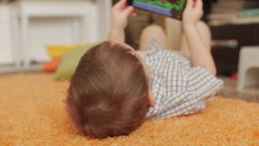 Cute little boy playing on the phone, playing with the tablet computer. stock footage Cute little boy playing on the phone, playing with the tablet computer. stock footage