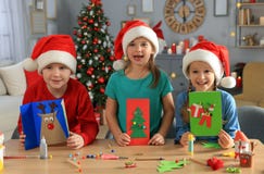 Cute Little Children In Santa Hats Making Beautiful Christmas Greeting Cards At Home Royalty Free Stock Photography