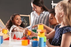 Cute little children and nursery teacher playing with building blocks in kindergarten royalty free stock photos Cute little children and nursery teacher playing with building blocks in kindergarten royalty free stock photos
