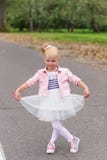 A cute little girl in a beautiful dress and sneakers playing on Royalty Free Stock Images A cute little girl in a beautiful dress and sneakers playing on Royalty Free Stock Images