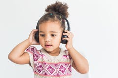 Cute little girl in a colorful dress listening to music with headphones on a white background royalty free stock photography Cute little girl in a colorful dress listening to music with headphones on a white background royalty free stock photography