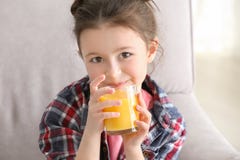 Cute little girl drinking juice while sitting on sofa at home Stock Images Cute little girl drinking juice while sitting on sofa at home Stock Images