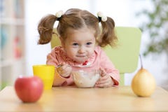 Cute little girl eating yogurt at home stock photos Cute little girl eating yogurt at home stock photos
