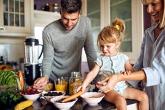 Cute little girl with parents preparing breakfast stock photo Cute little girl with parents preparing breakfast stock photo