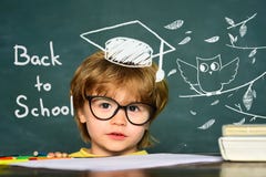 Cute little preschool kid boy in a classroom. Blackboard background. Teachers day. Kids from primary school. September 1