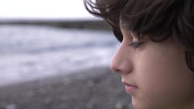 A cute teenager with curly hair against the backdrop of the sea. 4k, slow motion stock video A cute teenager with curly hair against the backdrop of the sea. 4k, slow motion stock video