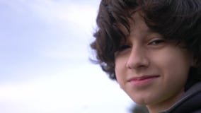 Cute teenager with curly hair against the blue sky 4k, slow-motion shooting stock footage Cute teenager with curly hair against the blue sky 4k, slow-motion shooting stock footage