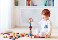 Cute toddler baby boy playing with wooden blocks, building a balancing high tower stock photography Cute toddler baby boy playing with wooden blocks, building a balancing high tower stock photography