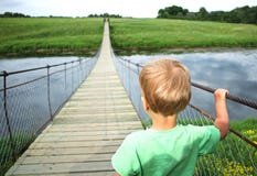 Cute toddler boy on a suspension bridge across the river. Adventure travel, look into the future, opening a new way concept. Stock Images Cute toddler boy on a suspension bridge across the river. Adventure travel, look into the future, opening a new way concept. Stock Images