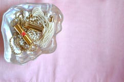 Cuvette nacrée de coquille avec des perles, des rouges à lèvres et des bijoux d'or sur le fond en soie rose avec l'espace de copi Photographie stock libre de droits Cuvette nacrée de coquille avec des perles, des rouges à lèvres et des bijoux d'or sur le fond en soie rose avec l'espace de copi Photographie stock libre de droits