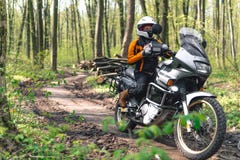 Cyklistflicka som bär en motorcykeldräkt, skyddskläder, utrustning, touristic moped för affärsföretag med sidopåsar utomhus- arkivbild Cyklistflicka som bär en motorcykeldräkt, skyddskläder, utrustning, touristic moped för affärsföretag med sidopåsar utomhus- arkivbild