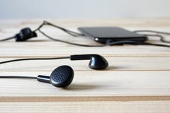 Czarni hełmofony łączyli telefon komórkowy na drewnianym stole zdjęcia stock Czarni hełmofony łączyli telefon komórkowy na drewnianym stole zdjęcia stock