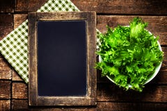 Czarny chalkboard dla menu i świeża sałatka nad drewnianym tłem obrazy stock Czarny chalkboard dla menu i świeża sałatka nad drewnianym tłem obrazy stock