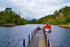 Czerwona łódź w portowym doku w sławnym jeziorze w Szkocja: Loch Kat obrazy stock Czerwona łódź w portowym doku w sławnym jeziorze w Szkocja: Loch Kat obrazy stock