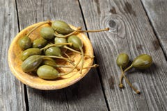 Câpres dans un plat jaune sur une table en bois grise Images stock Câpres dans un plat jaune sur une table en bois grise Images stock