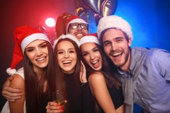Célébrant la nouvelle année ensemble Groupe des beaux jeunes dans des chapeaux de Santa jetant les confettis colorés, semblant he photographie stock libre de droits Célébrant la nouvelle année ensemble Groupe des beaux jeunes dans des chapeaux de Santa jetant les confettis colorés, semblant he photographie stock libre de droits
