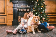 Círculo familiar de la Navidad del tema y del Año Nuevo Familia caucásica joven con el golden retriever de 1 año de Labrador de l fotografía de archivo libre de regalías Círculo familiar de la Navidad del tema y del Año Nuevo Familia caucásica joven con el golden retriever de 1 año de Labrador de l fotografía de archivo libre de regalías