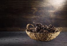 Cônes dans un panier en osier sur le fond foncé de cru image libre de droits Cônes dans un panier en osier sur le fond foncé de cru image libre de droits